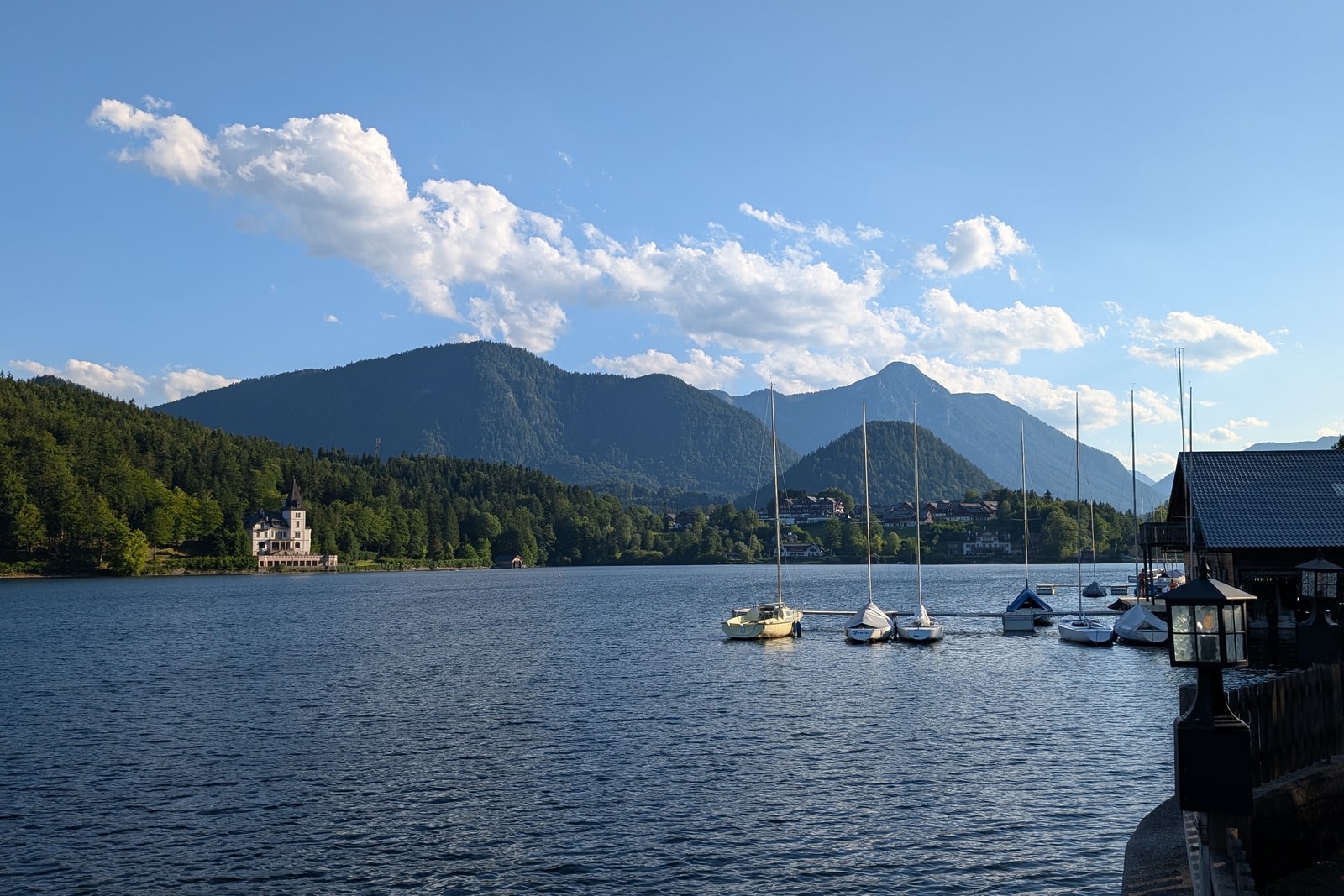 Blick über den Grundlsee mit Segelbooten, bewaldeten Ufern und Bergen am Horizont