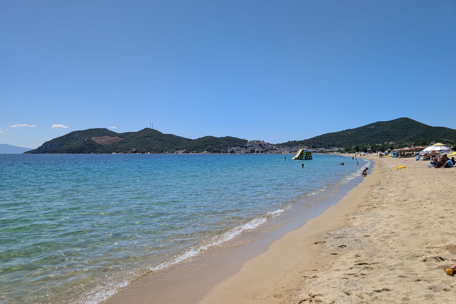 Klares blaues Wasser und der lange Sandstrand von Nea Iraklitsa vor grünen Hügeln